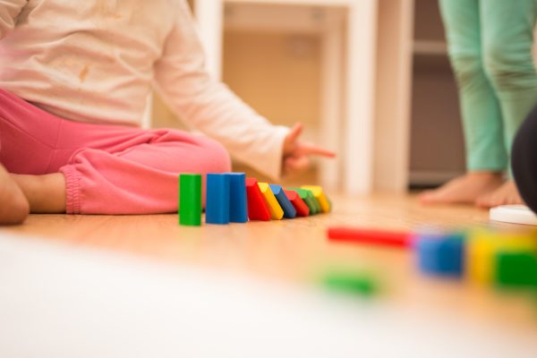 Kinde spielt mit Bauklötzen auf dem Boden